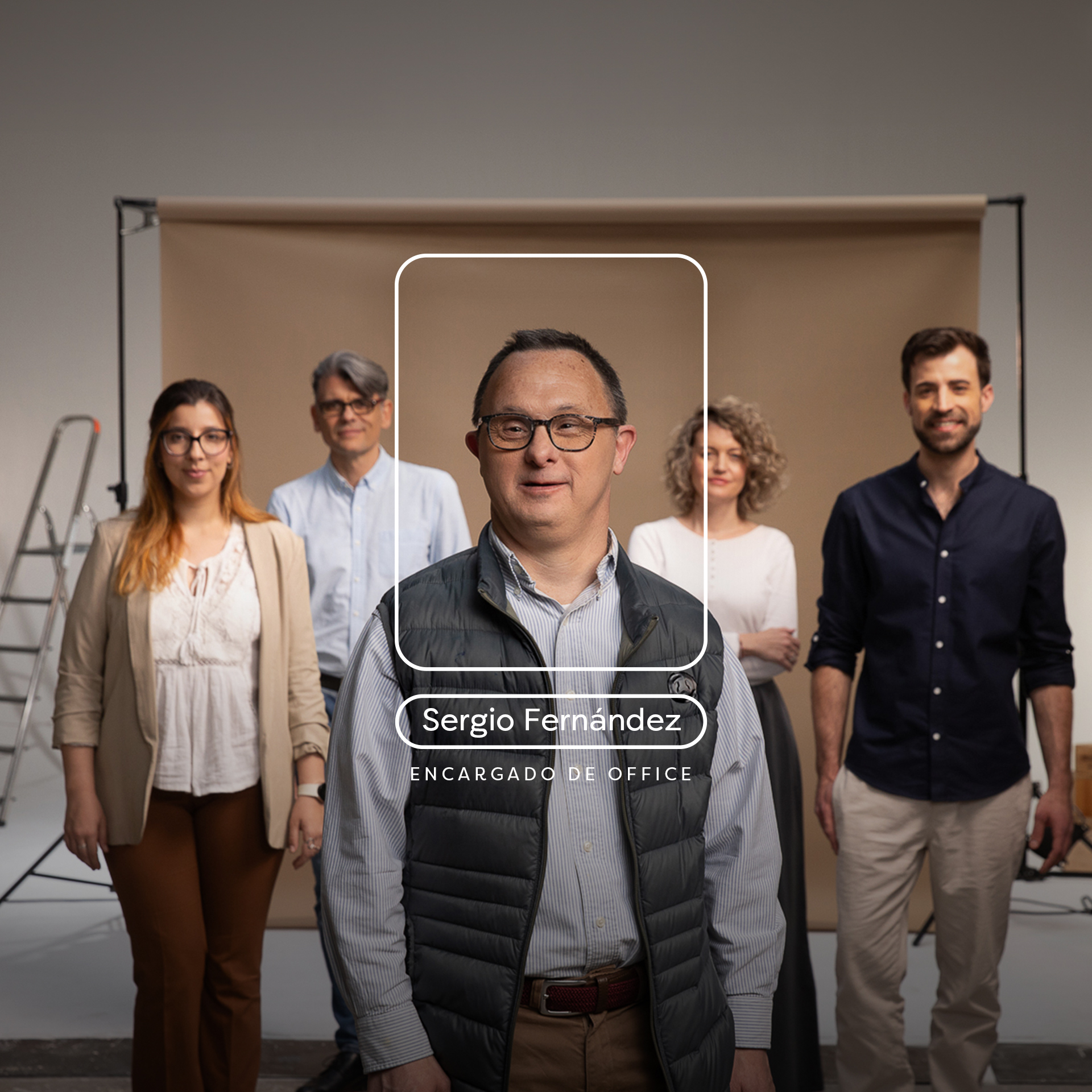 Grupo de personas en un estudio fotográfico con cuatro personas detras y un chico con gafas, camisa y chaleco destacando delante